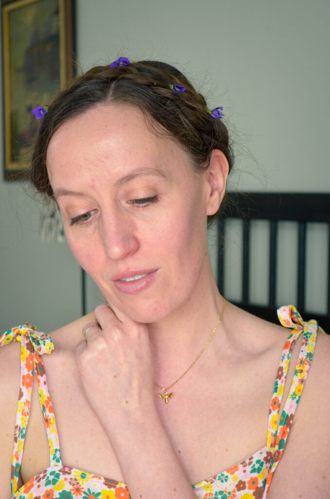 A woman in a floral nightgown with violets in her hair.
