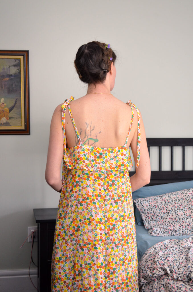 A woman in a floral nightgown, standing in a bedroom.