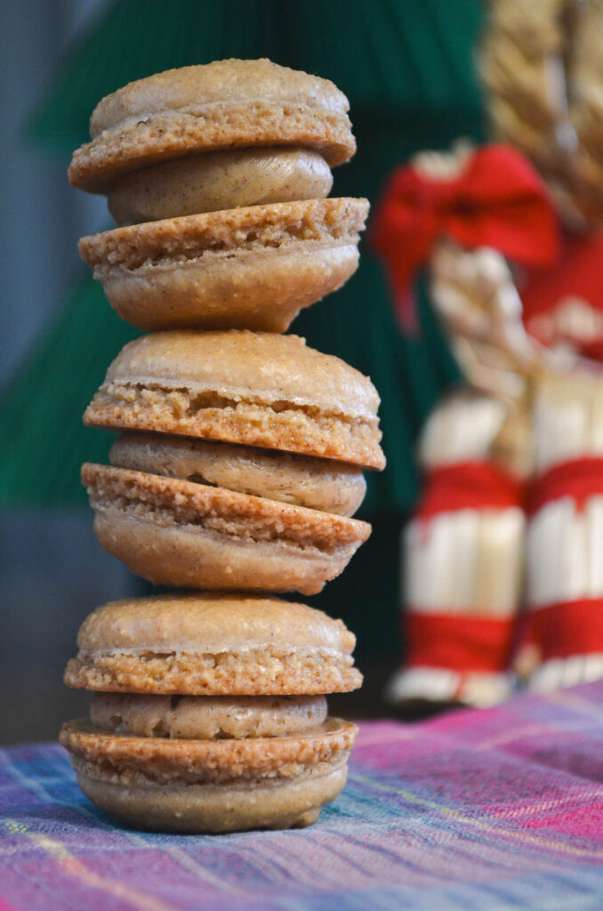 Three gingerbread macarons with small yule goat and paper tree decoration.